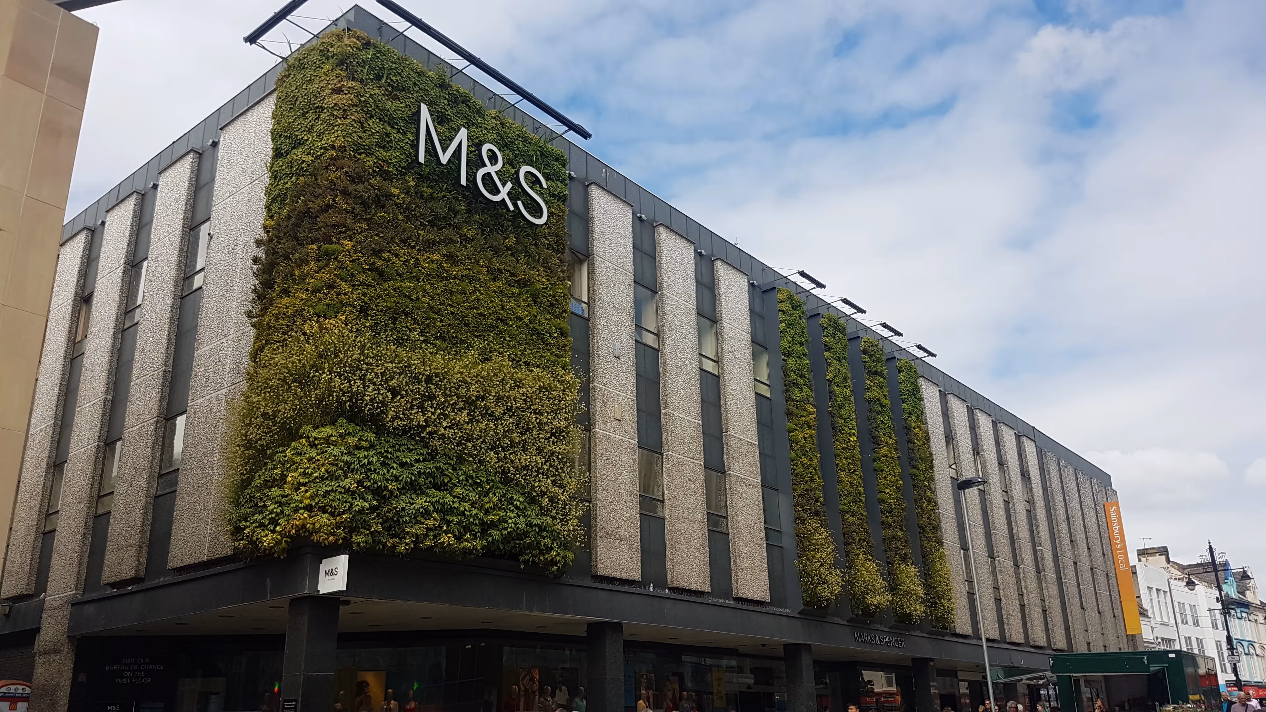 Image of a large Marks and Spencer, featuring exterior panels of living wall