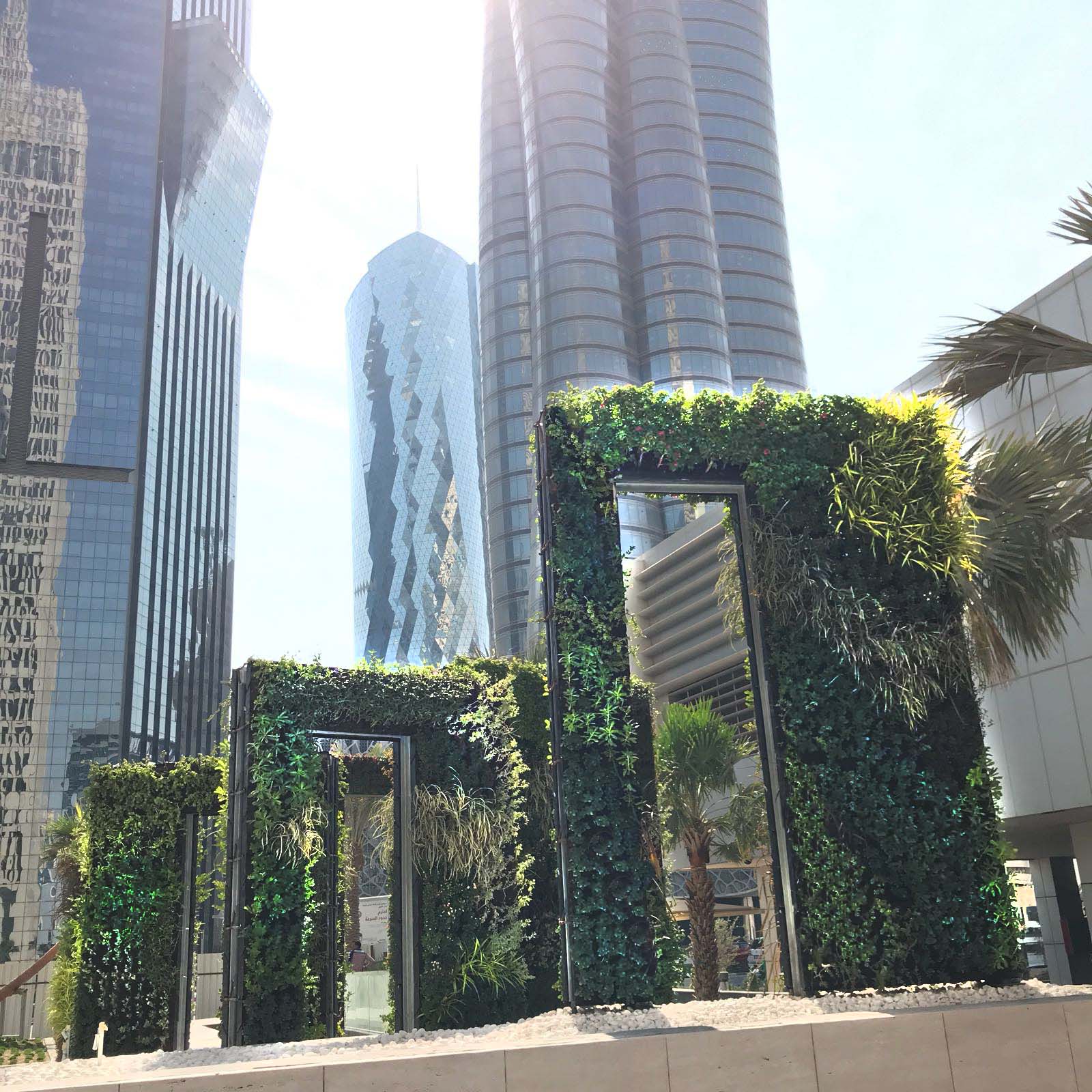 Green vertical gardens with glass frames against modern skyscrapers in city