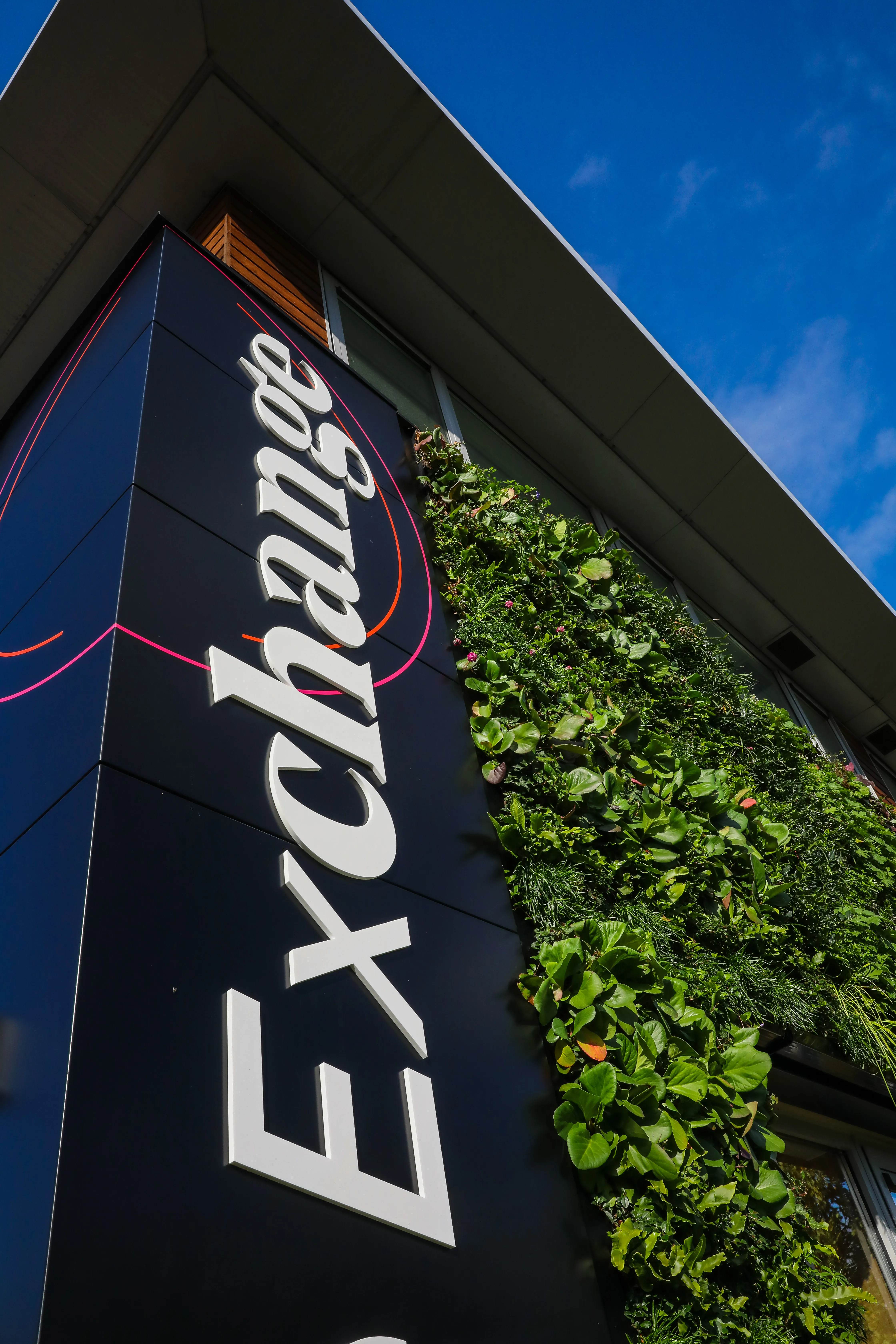 Exchange building with vertical garden and white logo against blue sky