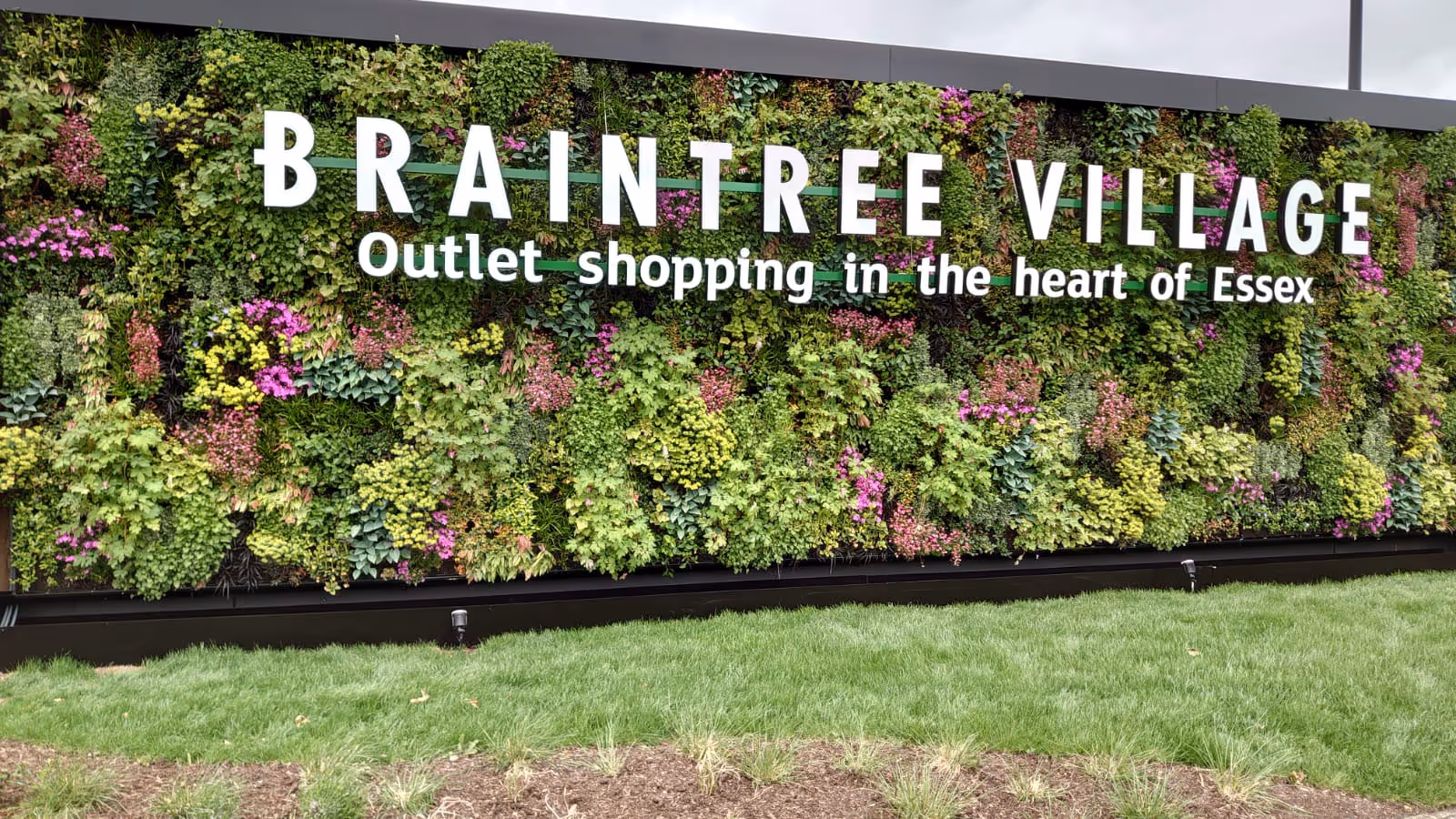 Lush green living wall with Braintree Village shopping outlet sign