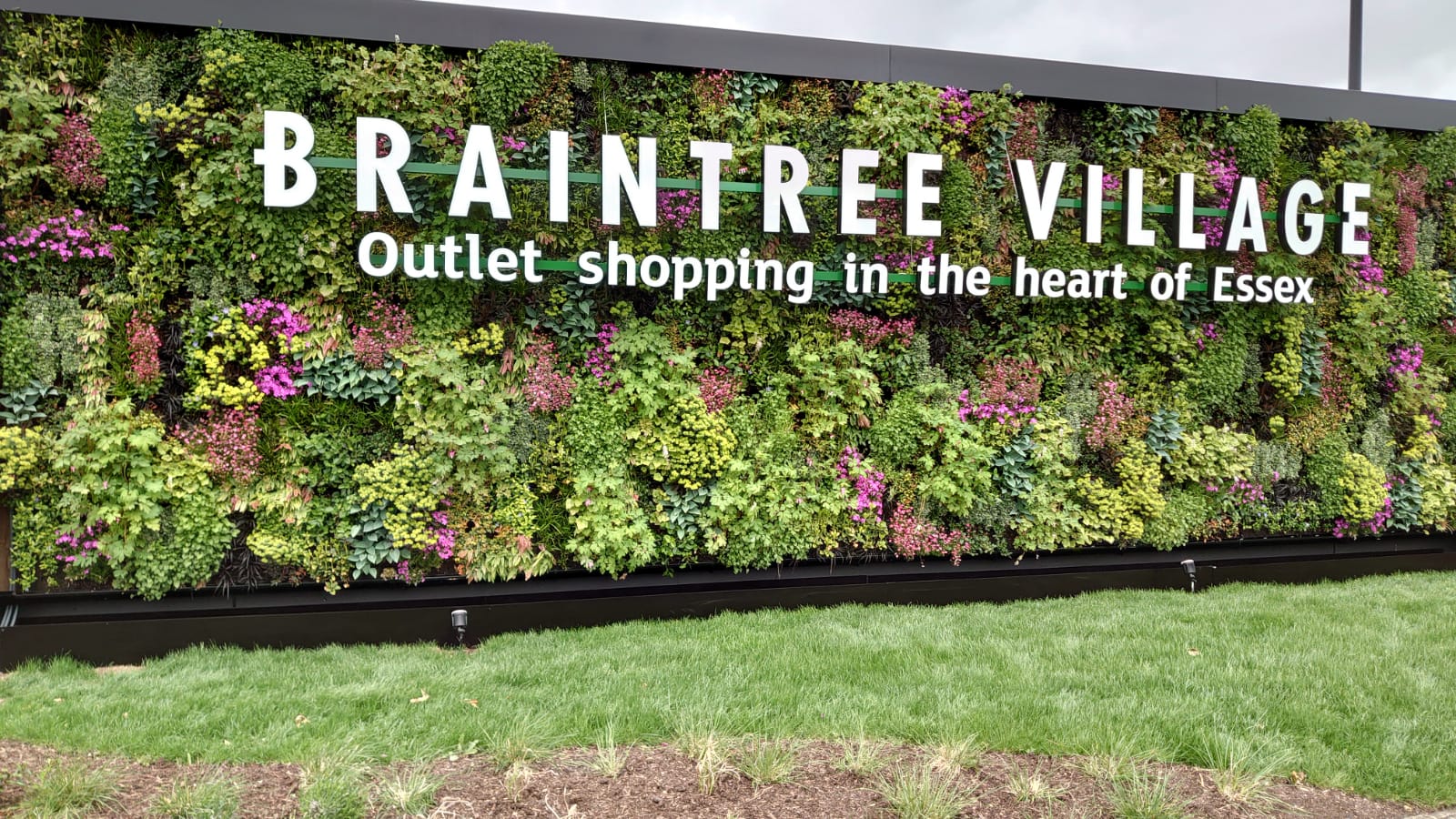 Lush green living wall with Braintree Village shopping outlet sign