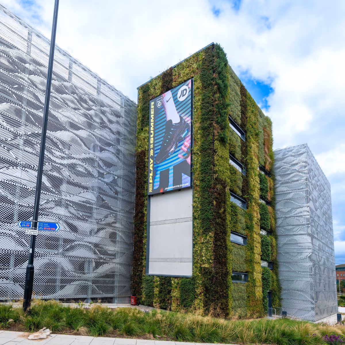 Green-covered building with JD advertisement and perforated metal exterior