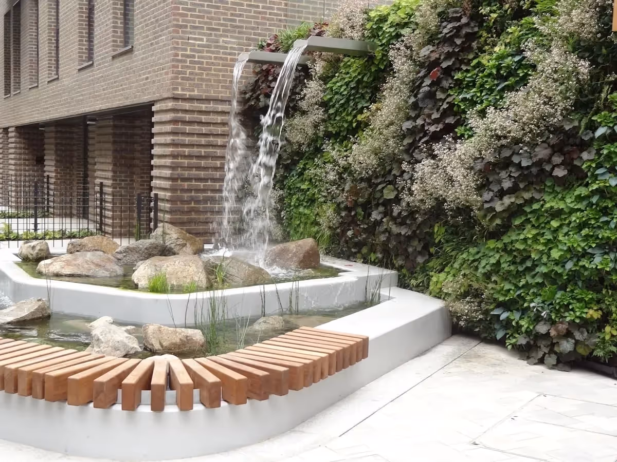Water feature coming out of a living wall with a building in the background 