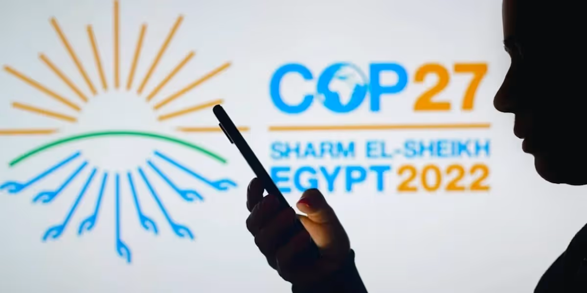 Outline of person on a phone in front of a screen advertising the COP27