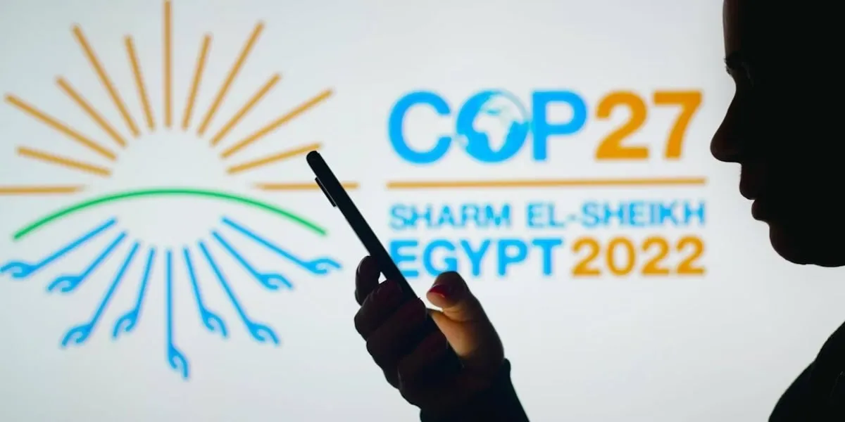Outline of person on a phone in front of a screen advertising the COP27