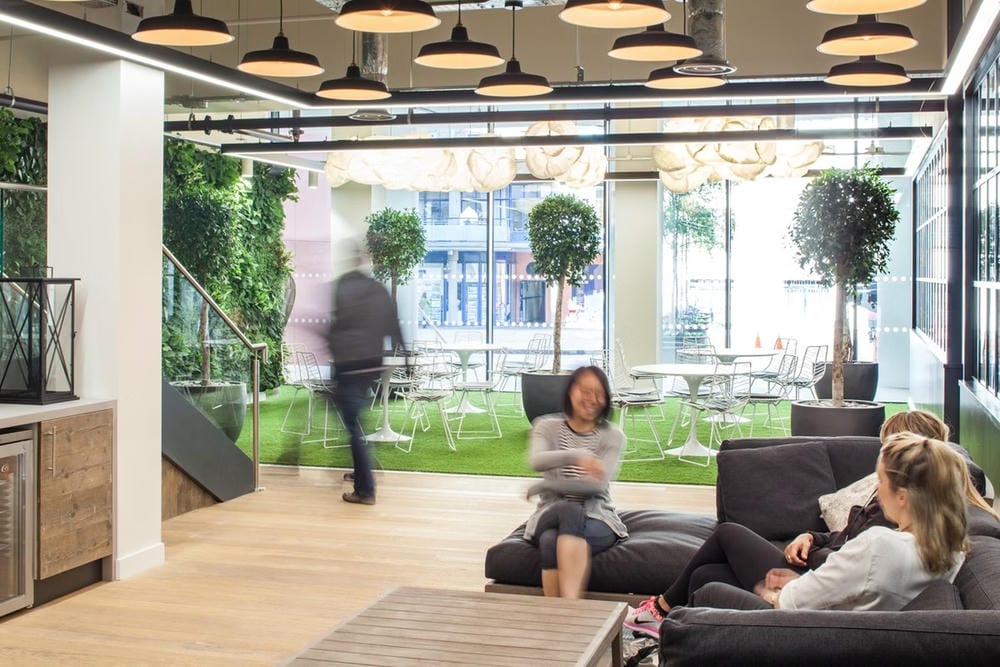 Inside Zoopla Property Group office, showing an interior living wall behind people sat on sofas.