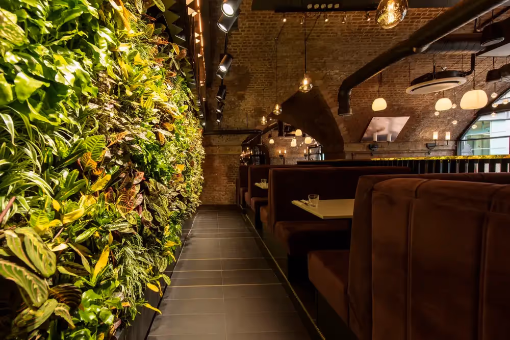 Interior of Manchester Gin Distillery, showing seating and an interio living wall 