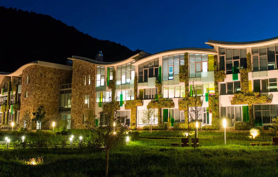 Modern green building complex illuminated at night with mountain backdrop