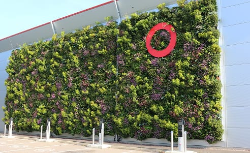 Living wall with vibrant green plants and red circle logo