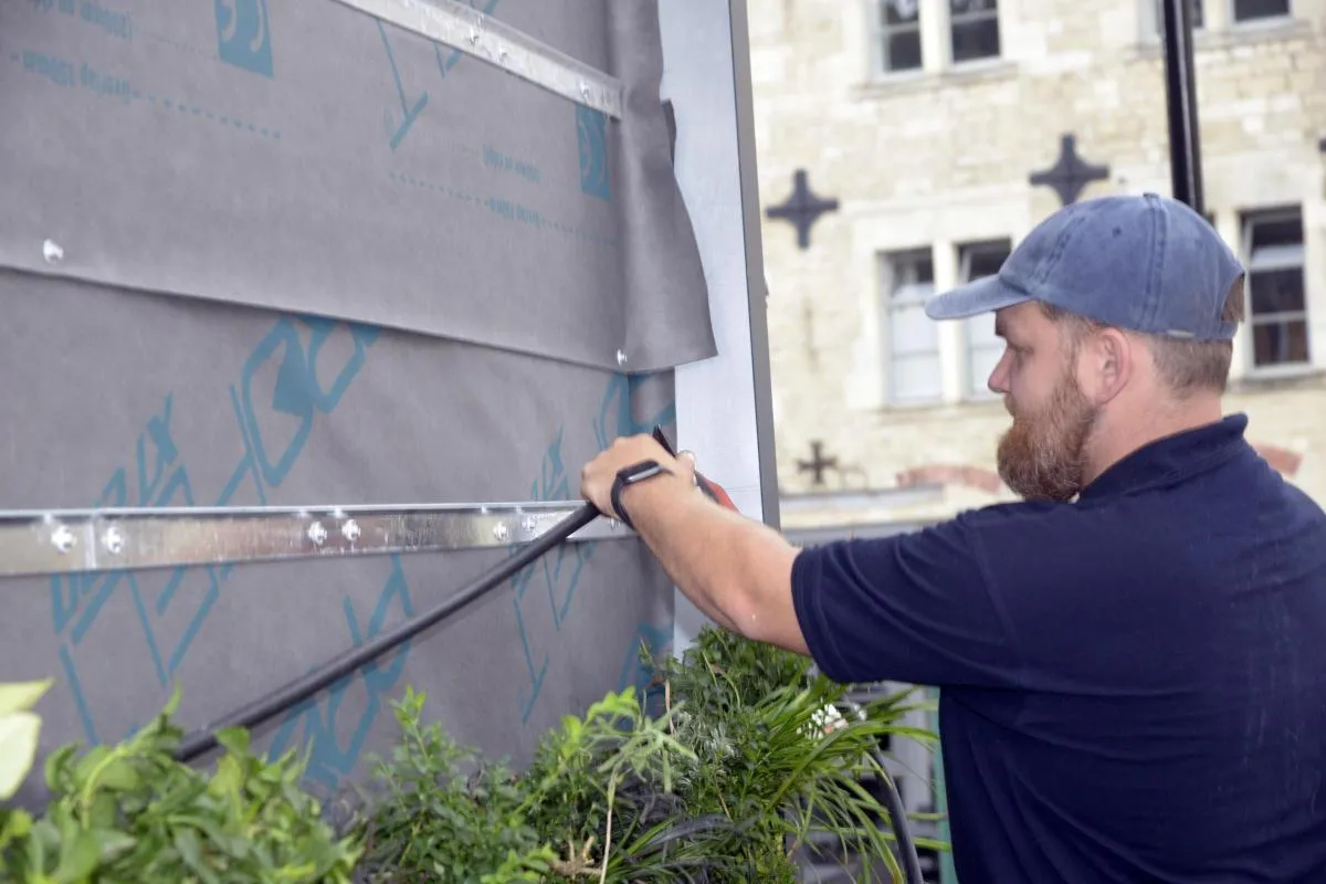 Worker in blue cap measuring and marking building exterior wall