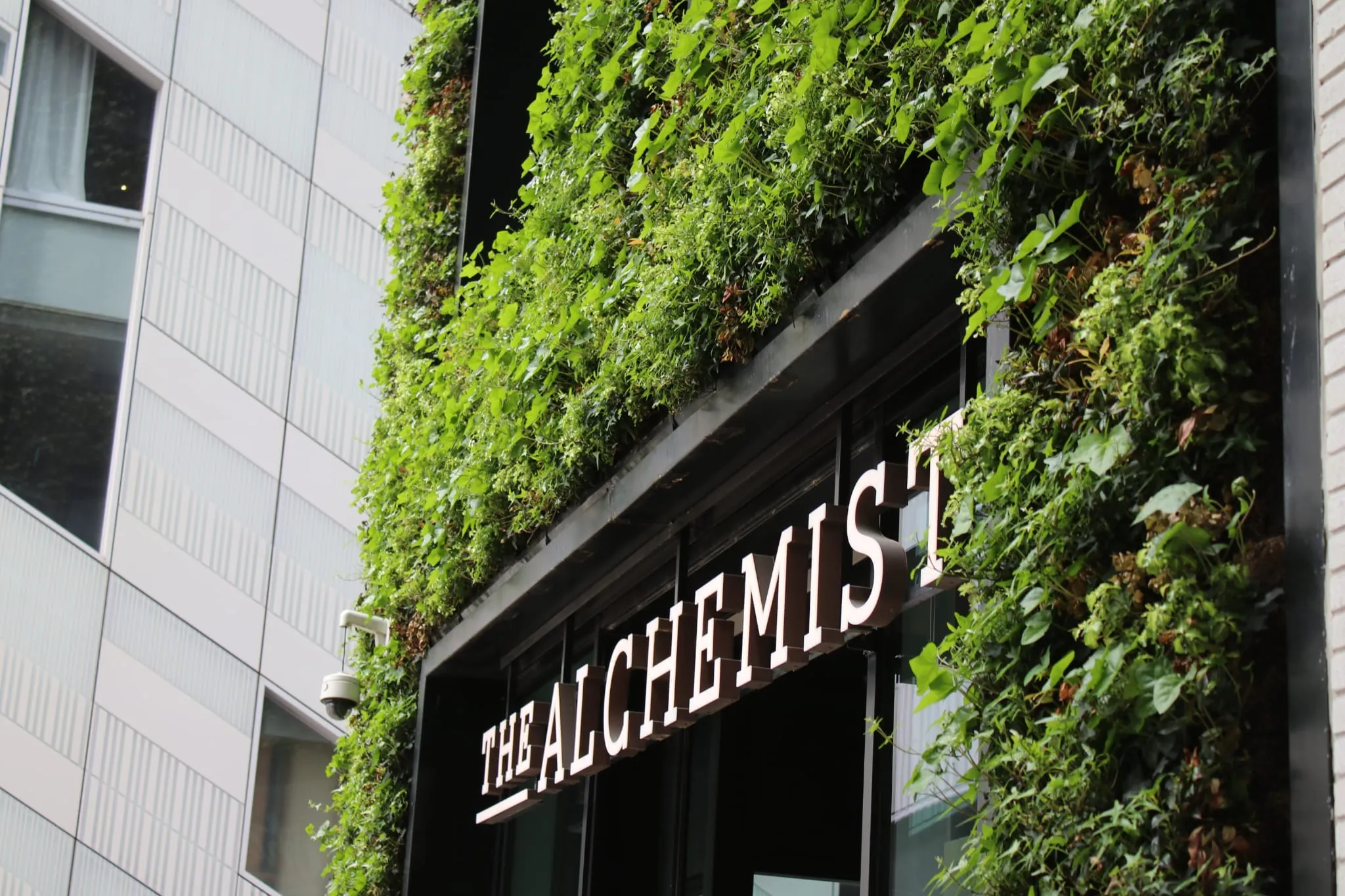 The Alchemist storefront with lush green vertical garden on building facade