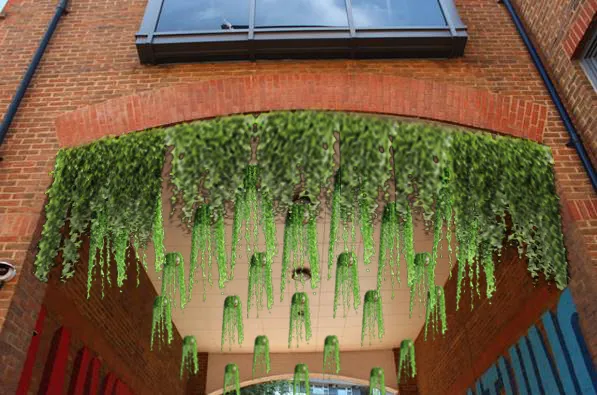 Lush green hanging plants cascading over brick building entrance arch