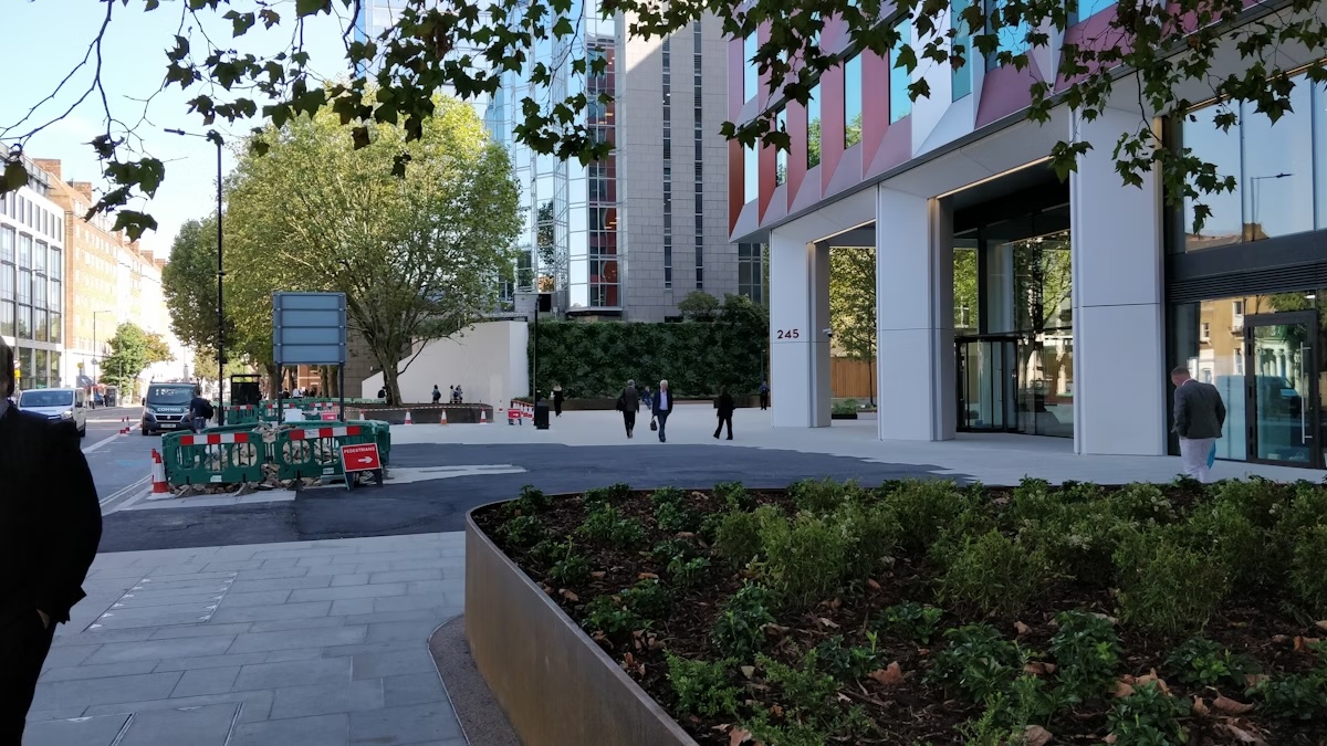 Urban street scene with modern buildings, trees, and construction barriers