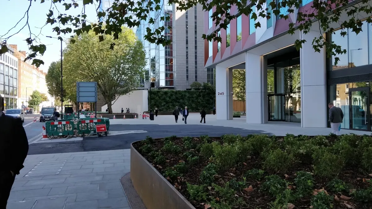 Urban street scene with modern buildings, trees, and construction barriers