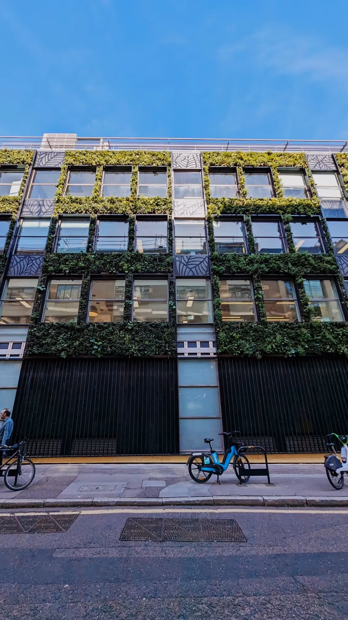 Green-covered modern office building with bikes parked on urban street