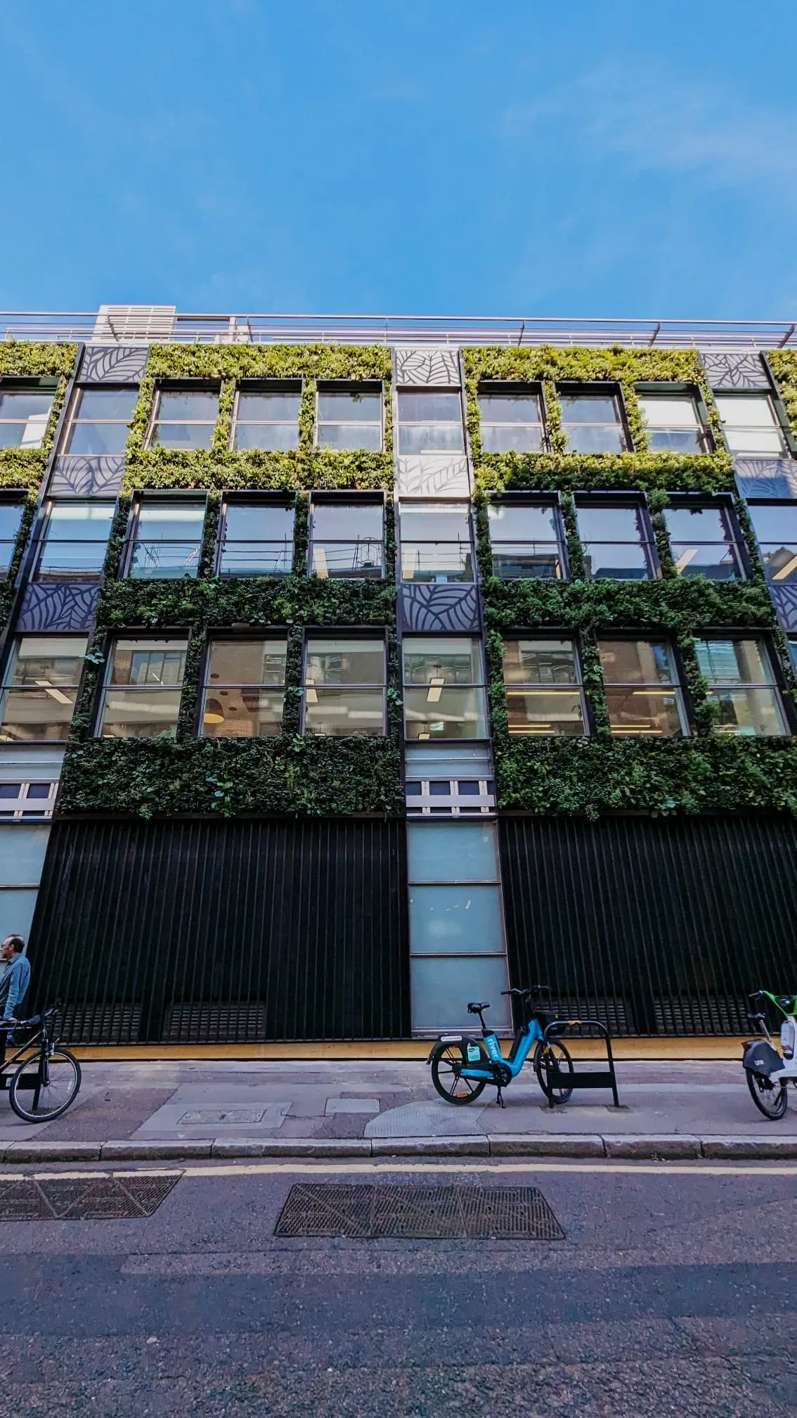 Green-covered modern office building with bikes parked on urban street