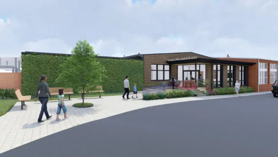 Modern building exterior with landscaped walkway and people walking near entrance