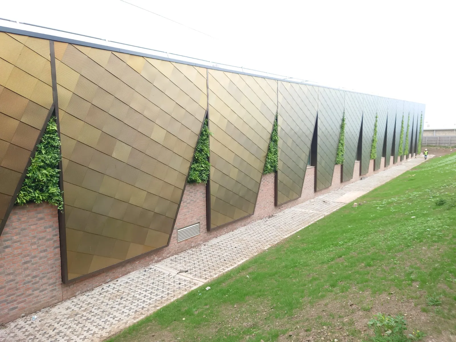 Modern building wall with green vertical gardens and geometric metal panels