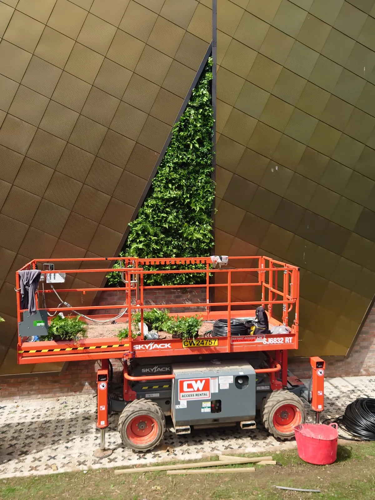 Skyjack lift platform installing green wall on modern geometric building