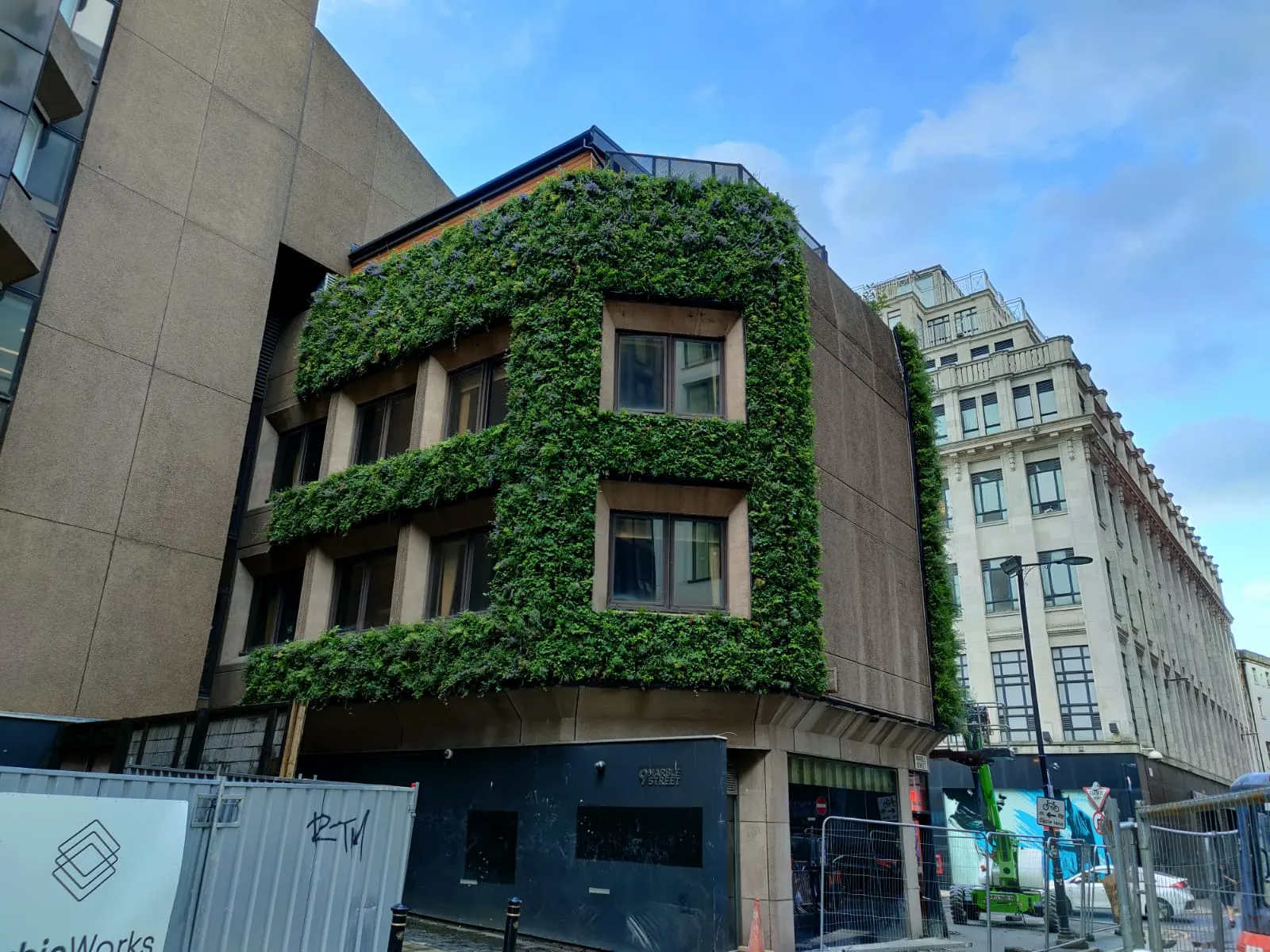 Green-covered urban building with lush vertical garden facade