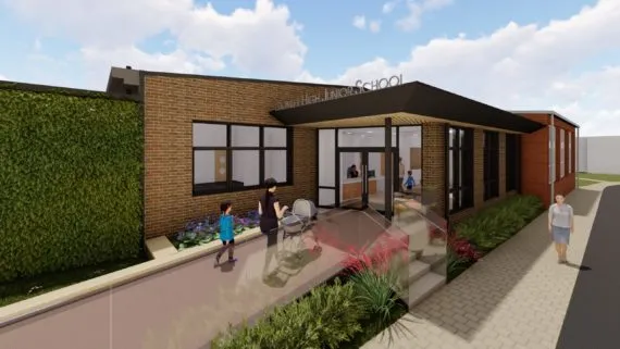 Modern school building exterior with landscaping and people walking outside