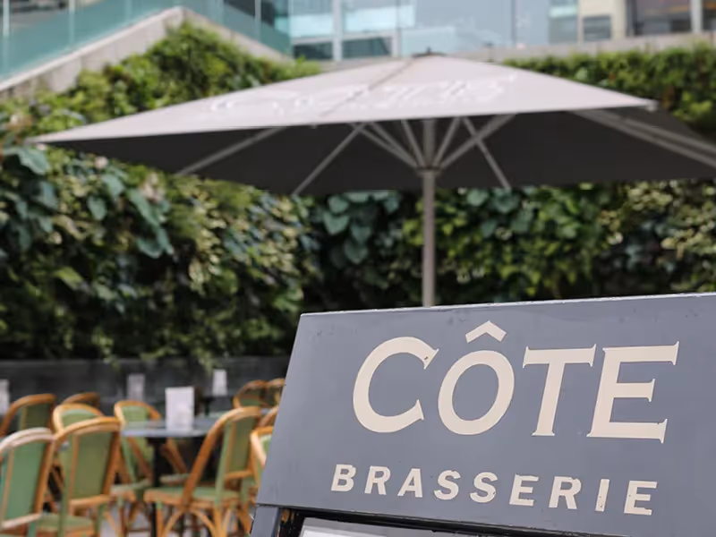 Côte Brasserie outdoor seating area with umbrella and chairs