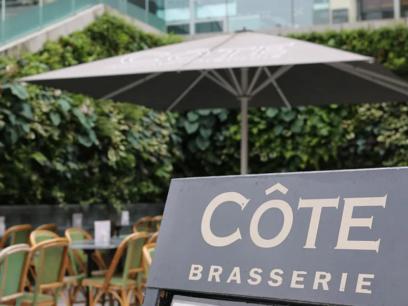 Côte Brasserie outdoor seating area with umbrella and chairs