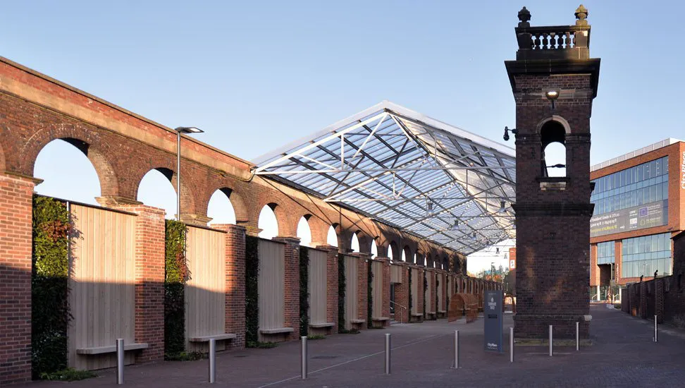 Historic brick arches and modern glass roof with bell tower