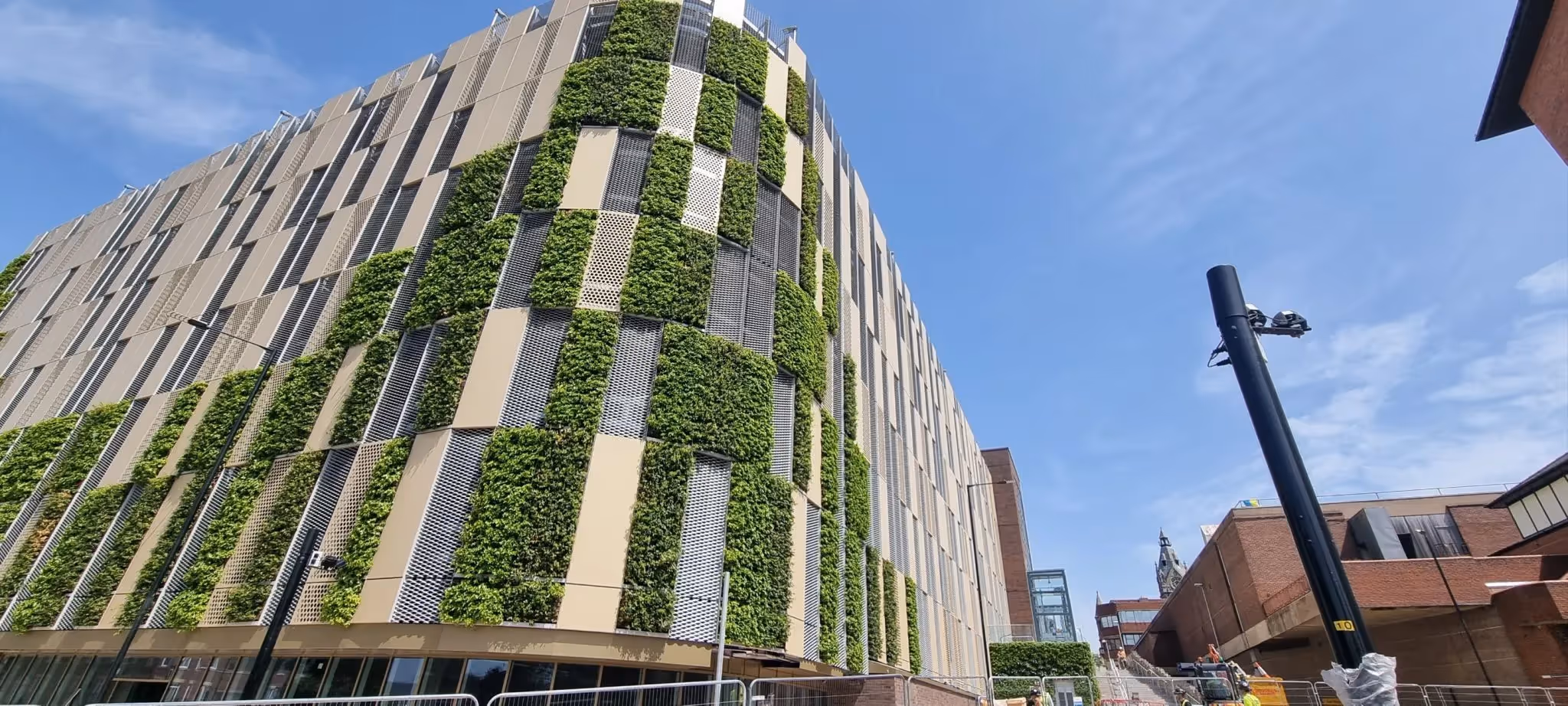 Modern building with vertical green walls and metal panels against blue sky