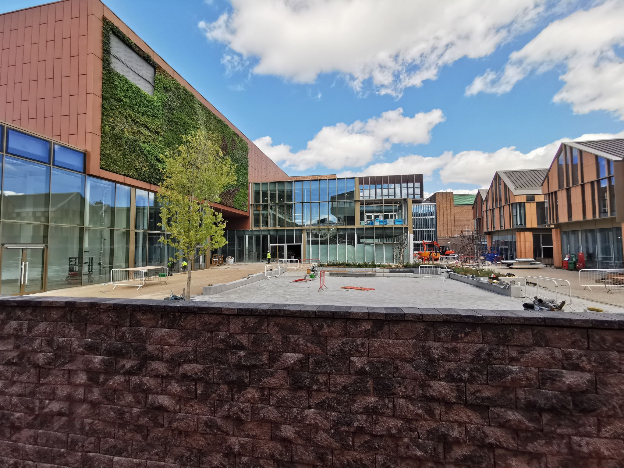 Modern campus building with green wall, glass windows, and construction site