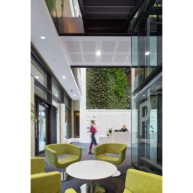 Modern office lobby with green chairs, white table, and living green wall