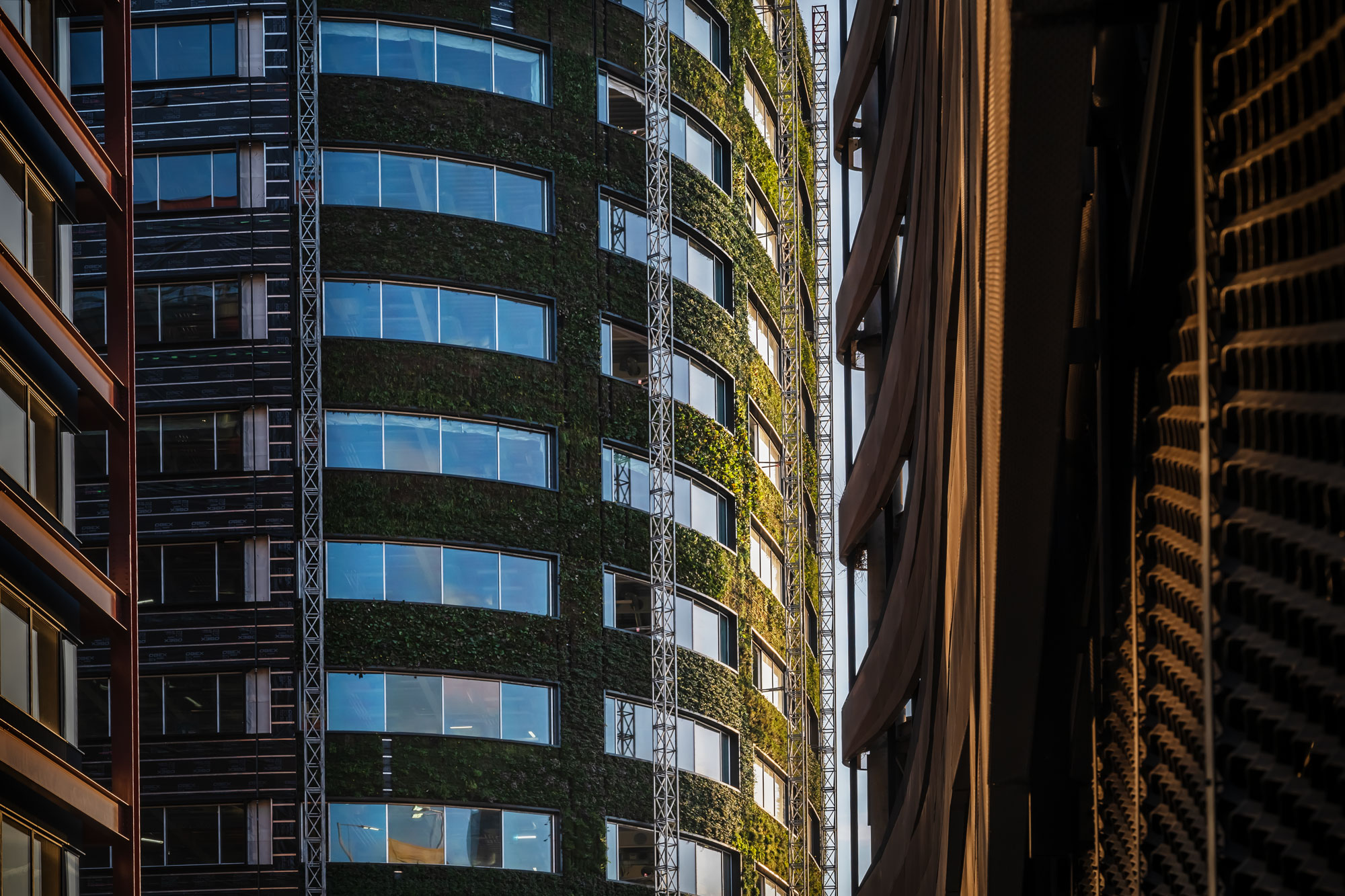 Modern curved building with green living walls and glass windows