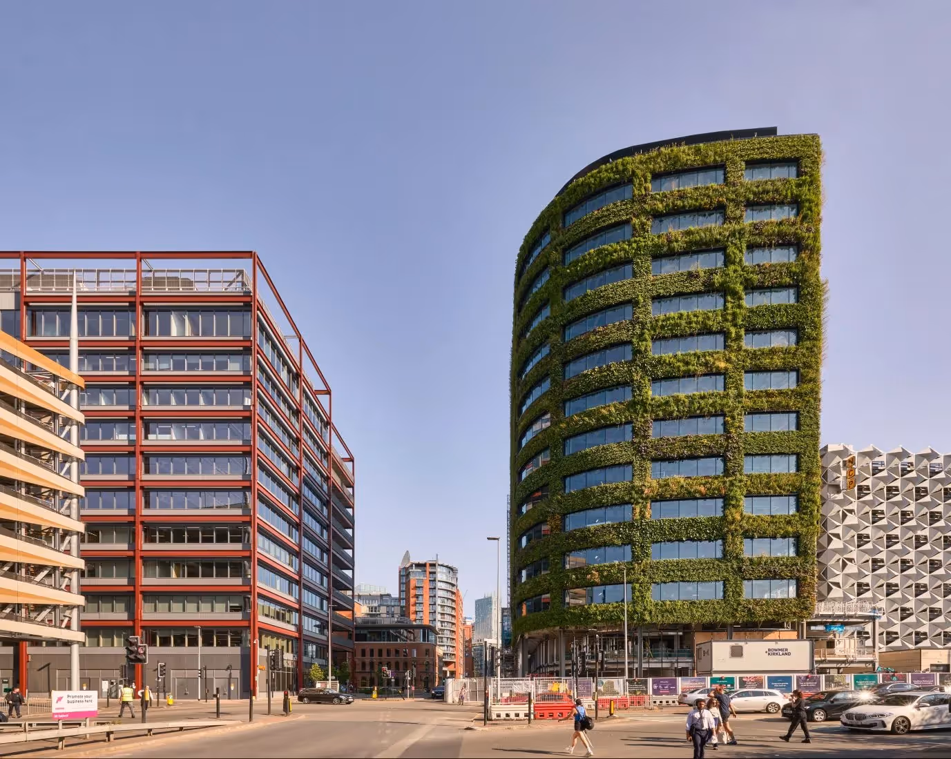 Modern green vertical garden skyscraper next to red office building