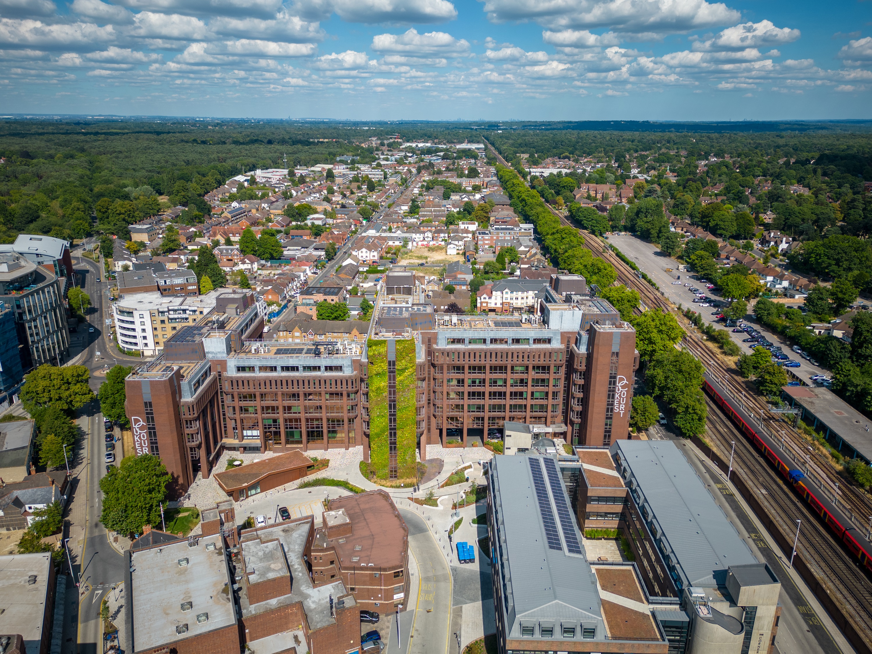 Aerial view of suburban town with modern buildings, railway, and green landscape