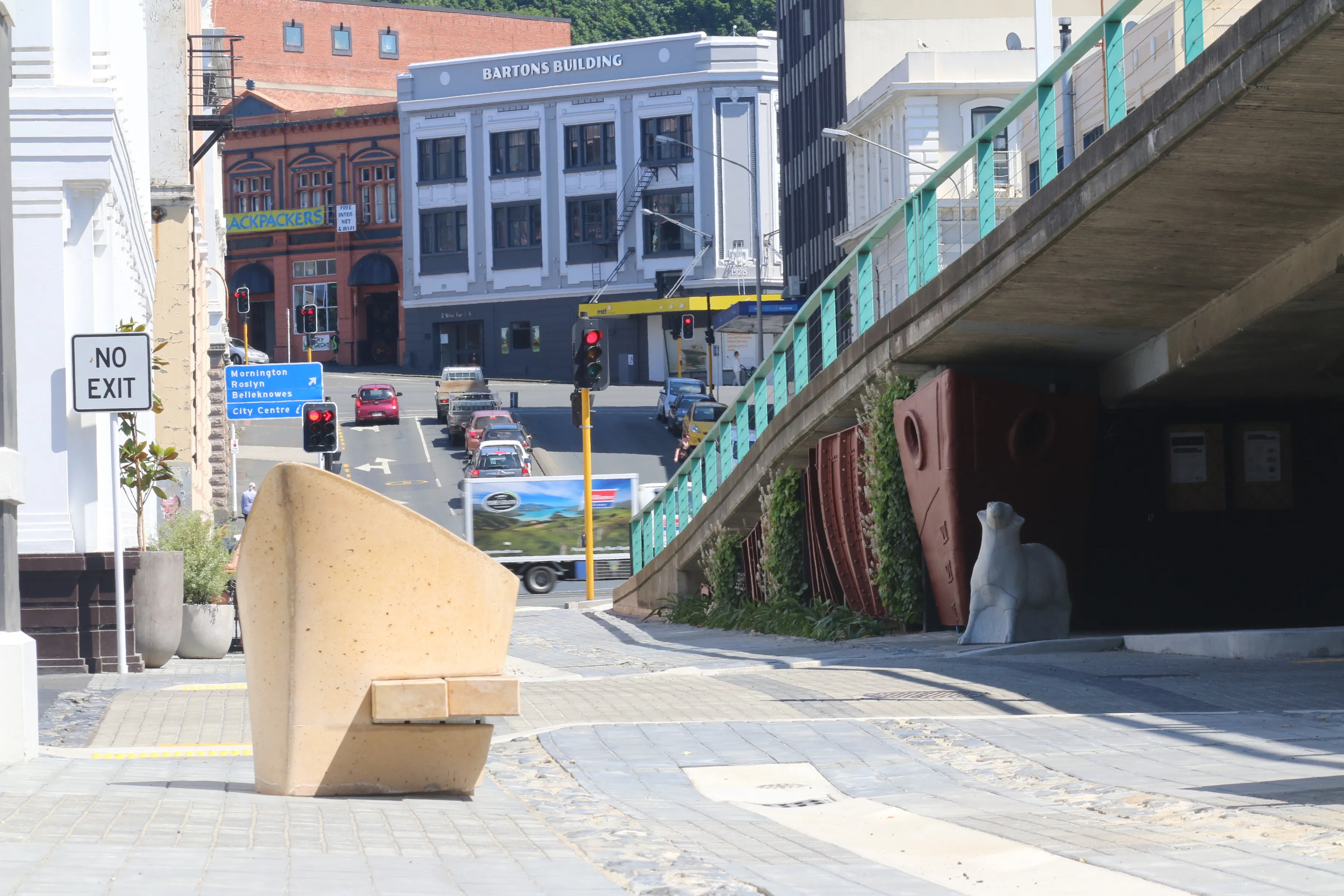 Urban street scene with Bartons Building, traffic lights, and stone sculpture