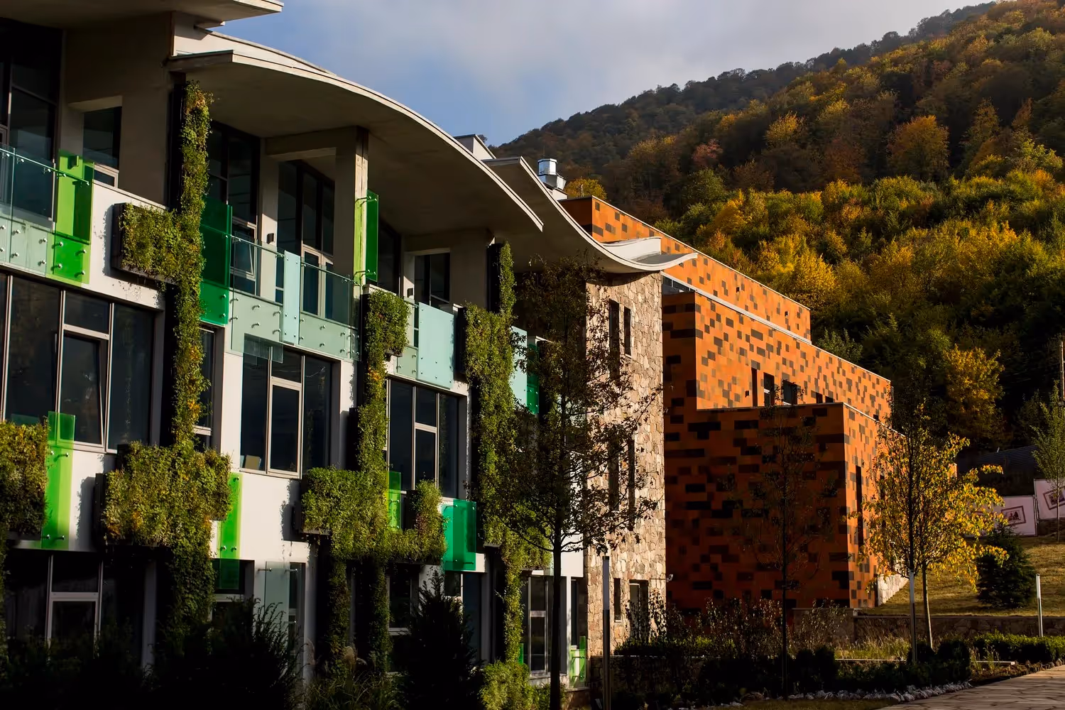 Modern green building with living walls nestled in autumn mountain landscape