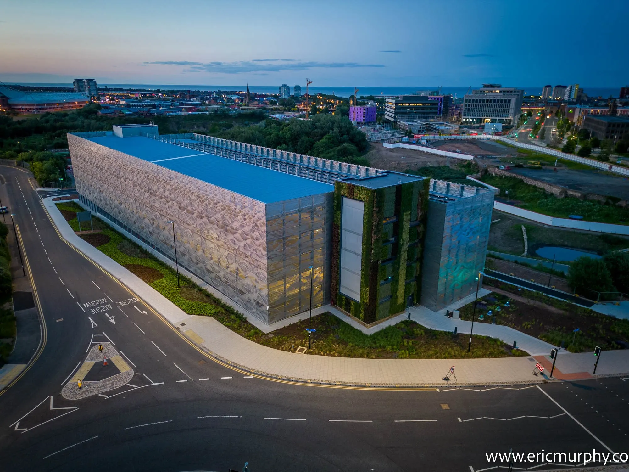 Modern architectural building with blue roof and green walls at dusk