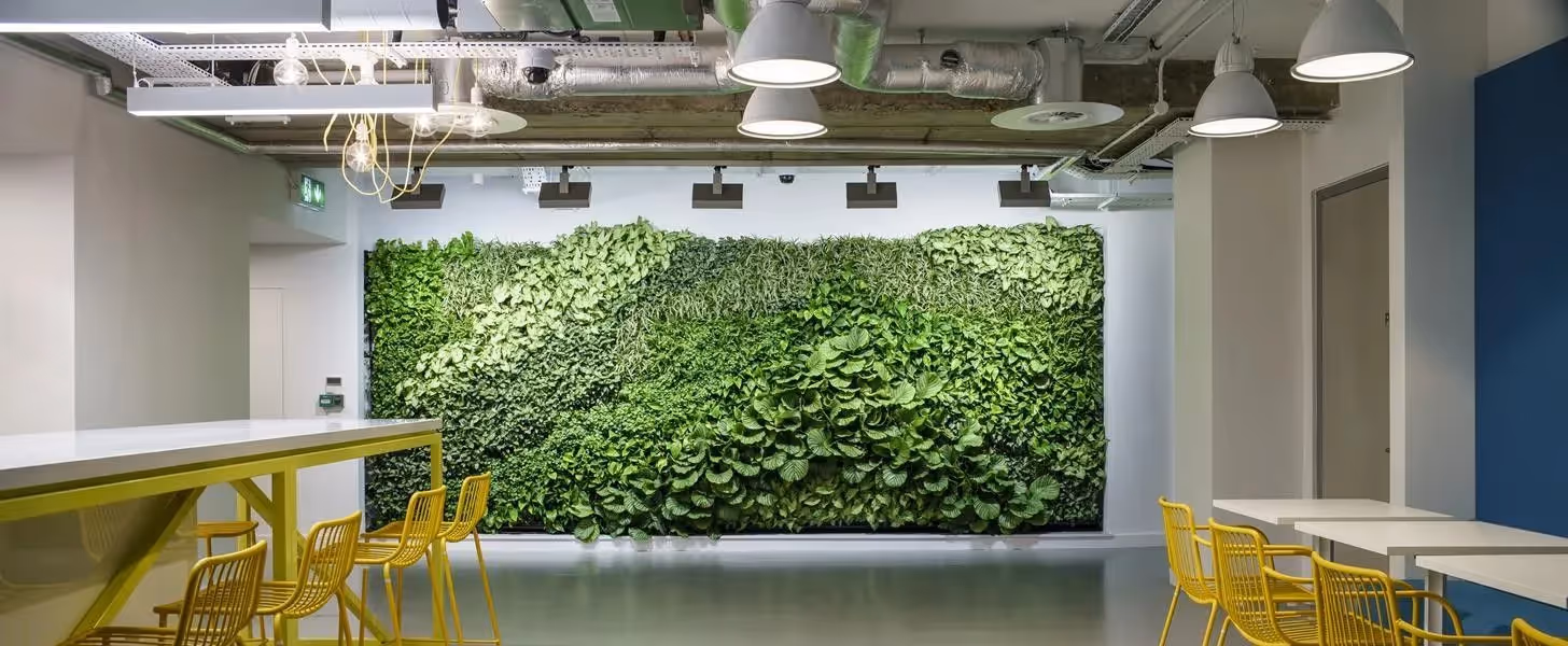 Green living wall with yellow chairs in modern office interior
