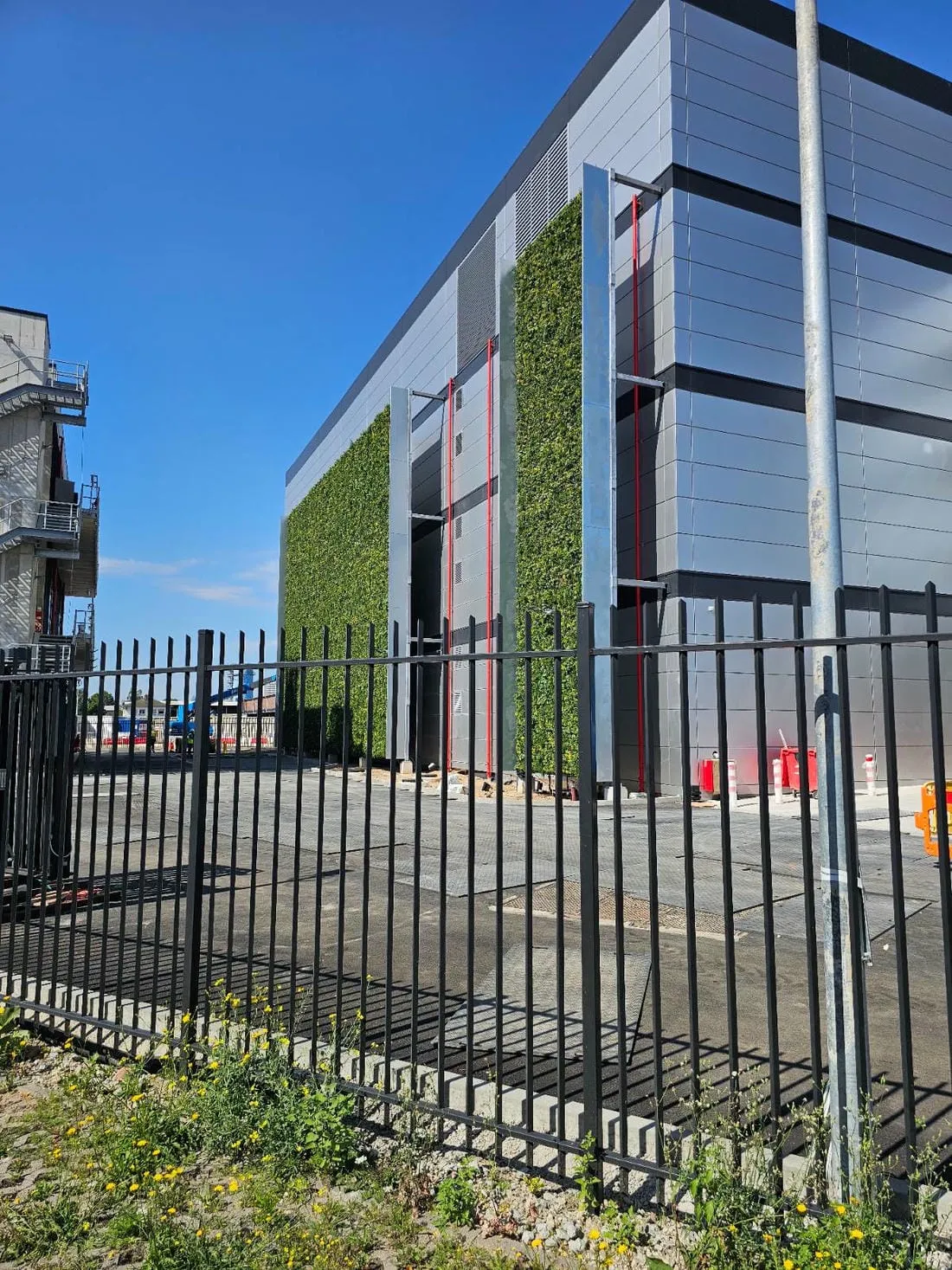 Modern building with green living wall behind black metal fence