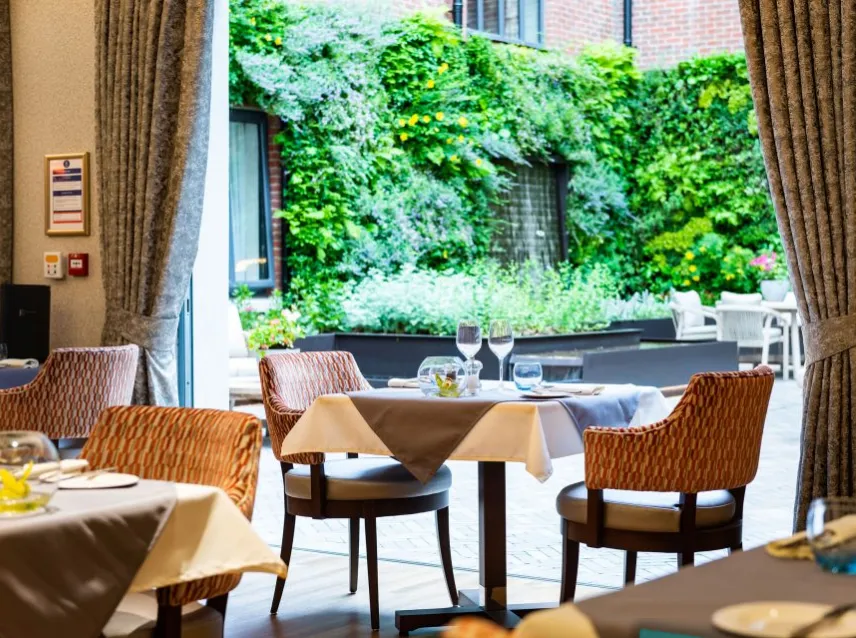 Restaurant interior with tables, chairs, and lush green garden view