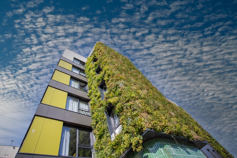 Living wall covers modern yellow and gray apartment building, The Mailbox in Stockport, against cloudy sky