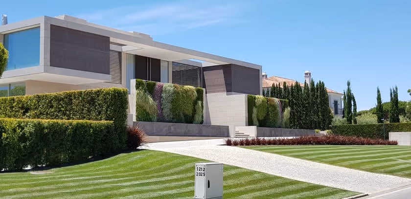 Modern home with living green wall and manicured lawn under blue sky