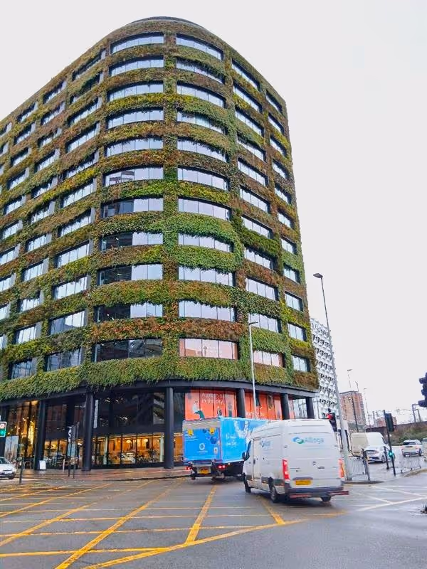 Eden's curved office building face with it's living wall 2 years after installation in a cloudy Manchester