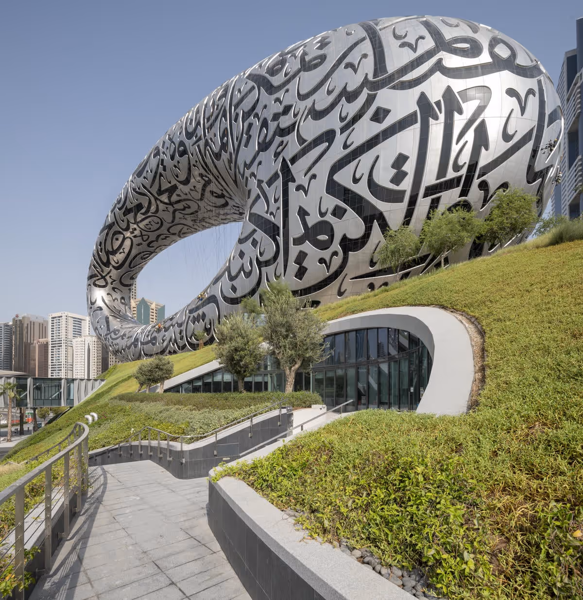 The walkway around the museum of the future with a curved arch running alongside it separating the living wall from the walkway