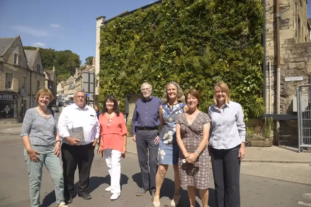 7 people stood smiling in front of the exterior wall in Bradford-on-Avon