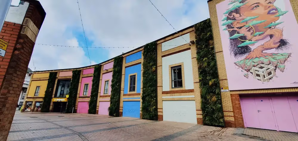 Pepper Lane, showing a courtyard where walls have strips of living wall and a mural