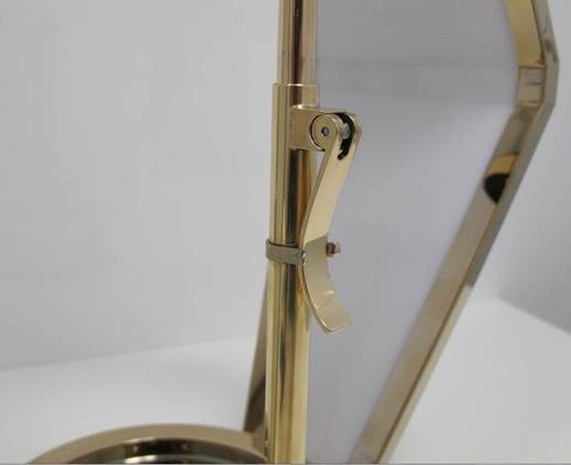 Close-up of a shiny brass lever attached to a vertical brass rod with a hexagonal frame in the background.