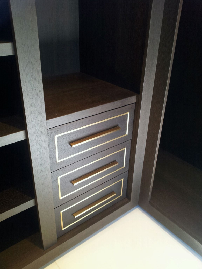 Dark wooden cabinet with three drawers featuring gold rectangular border accents and horizontal handles.
