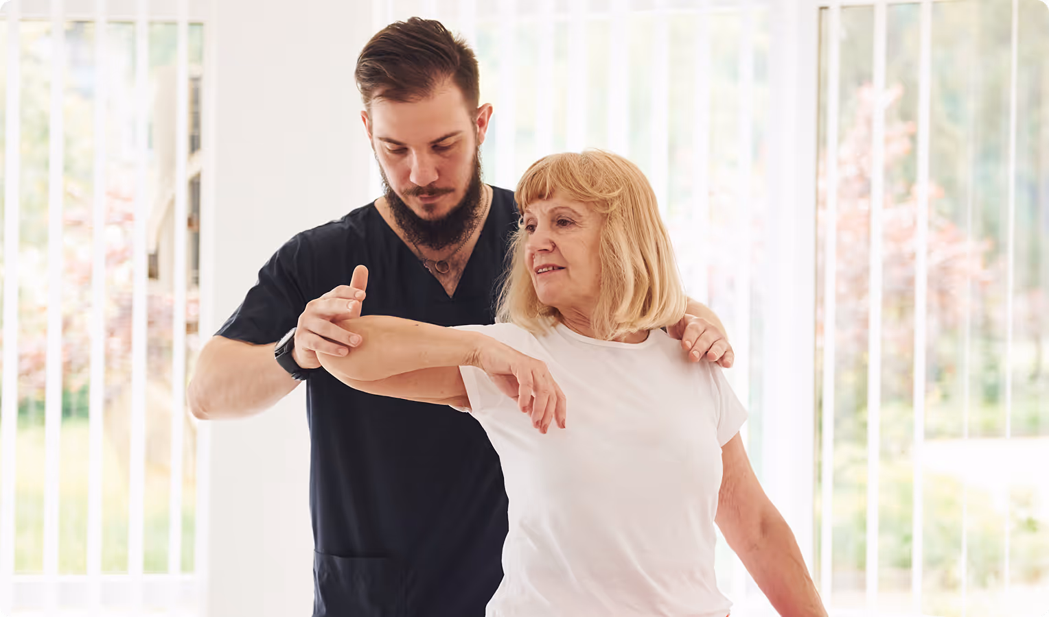 Caregiver assisting elderly woman with arm exercises