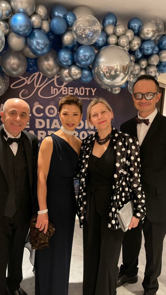 CC Kat and team in front of blue and silver ballon arch at award event